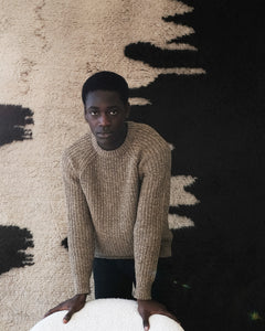 Model posing in front of the Diffusion rug, leaning on the Pierre Paulin F572 chair 