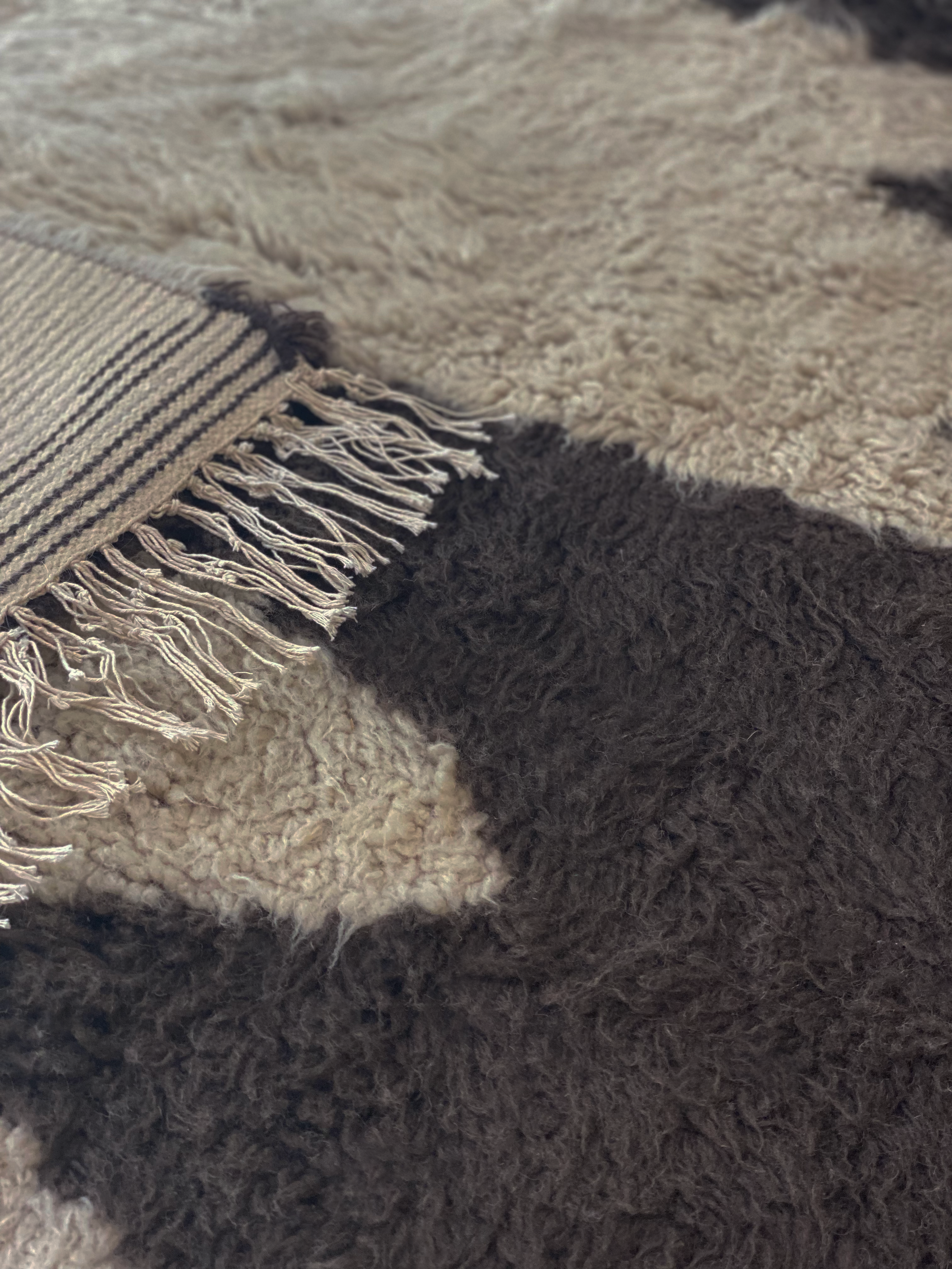 A close-up picture of the handmade artist rug made of 100% wool, showing details of the rug's knotting and color